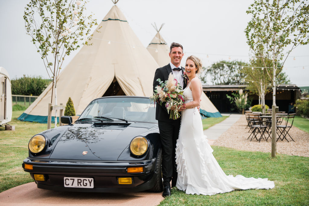 Wedding couple with Porsche at tipi wedding venue